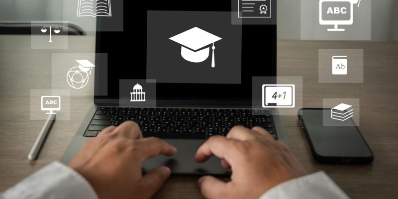 Person typing on a laptop displaying a graduation cap icon, surrounded by digital education symbols representing online learning and skill development.
