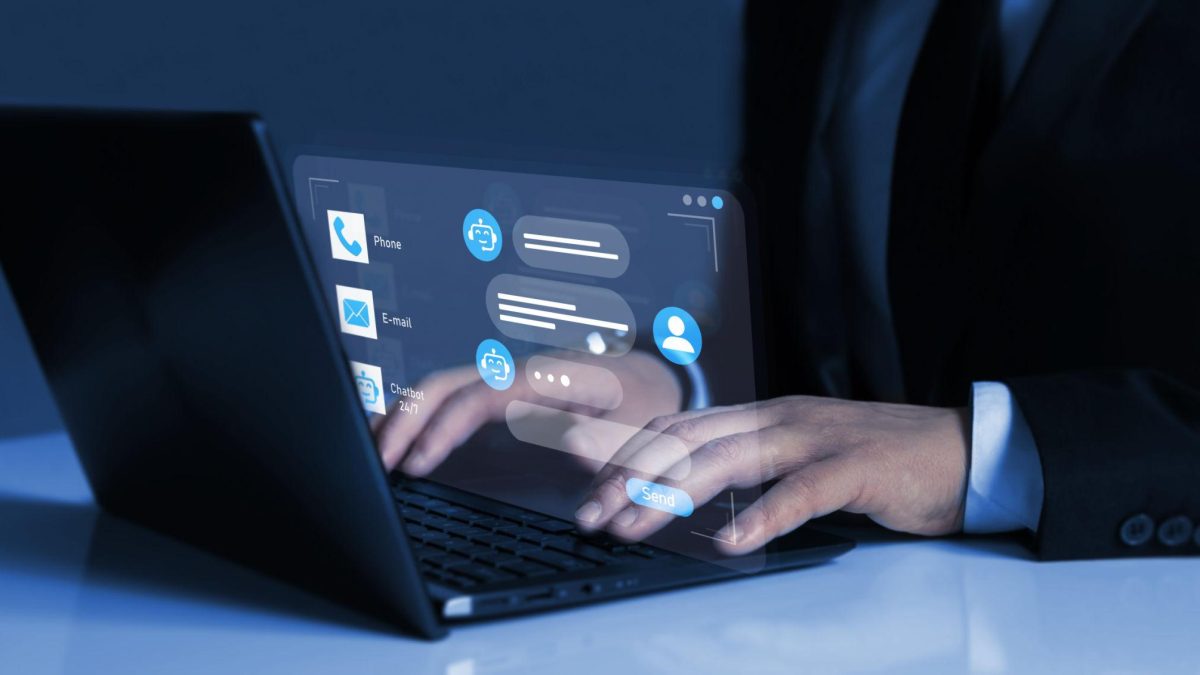 Person using a laptop with a virtual chatbot interface displayed on screen, showing automated customer support and digital communication icons.