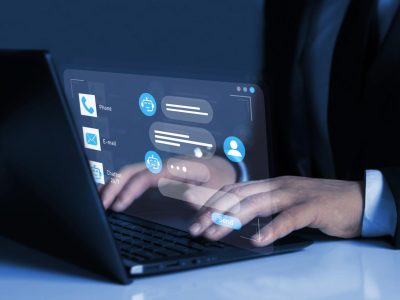 Person using a laptop with a virtual chatbot interface displayed on screen, showing automated customer support and digital communication icons.