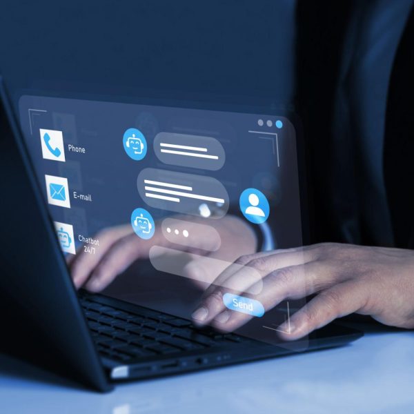 Person using a laptop with a virtual chatbot interface displayed on screen, showing automated customer support and digital communication icons.