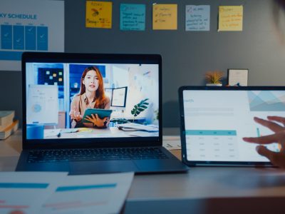 Student attending an online class on a laptop and tablet at home at night.