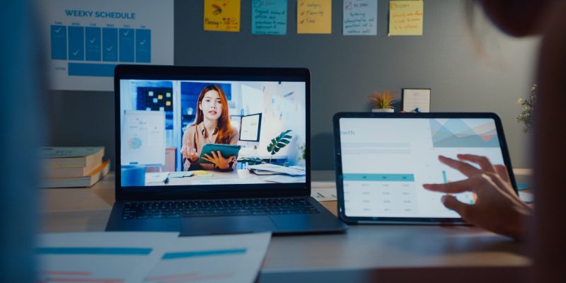Student attending an online class on a laptop and tablet at home at night.