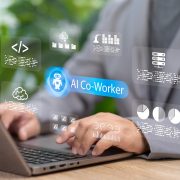 Professional using a laptop with a digital AI co-worker interface displayed on screen, featuring data analytics, cloud storage, coding, and workflow automation icons representing AI-powered workplace productivity and collaboration.